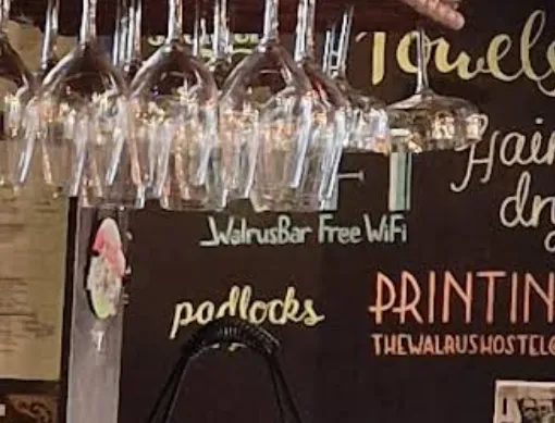 A sharp user photo of the reception chalkboard behind the bar: under a 'WIFI' heading it reads 'WalrusBar Free WiFi', with 'padlocks', 'PRINTING' and 'THEWALRUSHOSTEL…' around it