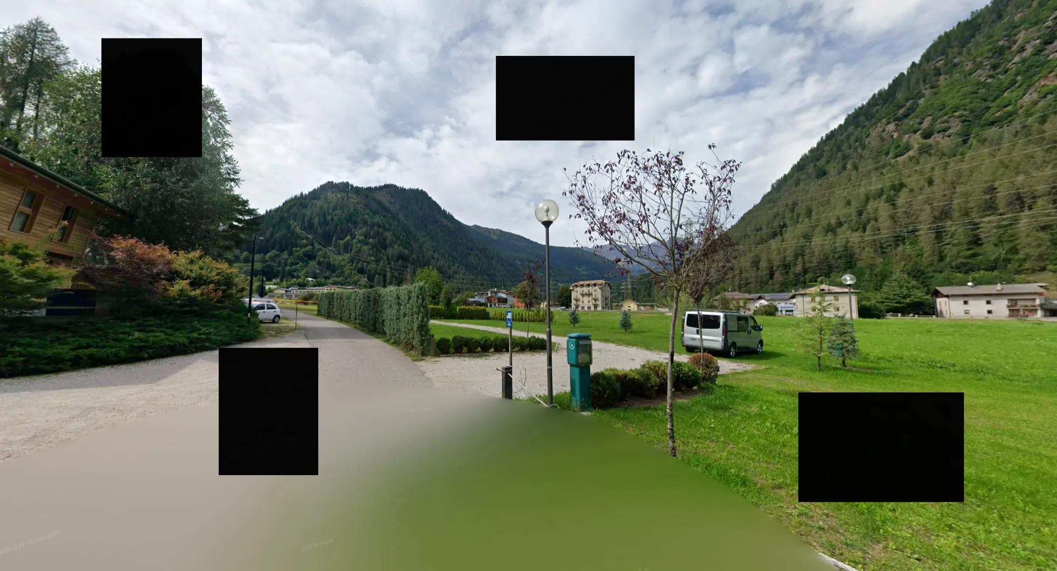 Four black squares cover every sign in the panorama — but they leave the valley profile, the ridge line and the vegetation untouched, which is all the geolocation actually needs