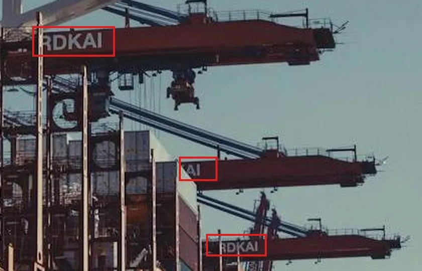 An enlarged crop of the red crane booms over the ship: red boxes around the letters RDKAI on three booms