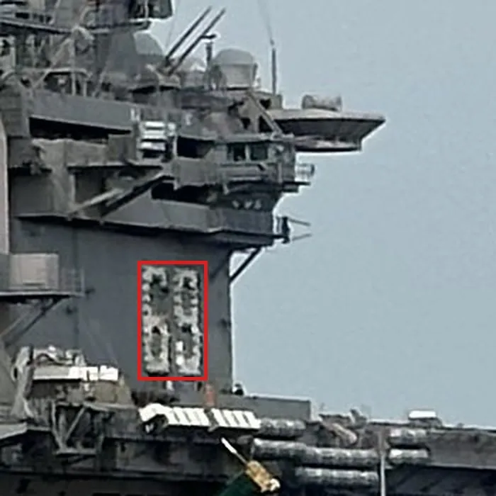 An enlarged crop of the right carrier's island at native resolution: two large white digits on the grey island wall in a red box, below the bridge windows and a radar platform