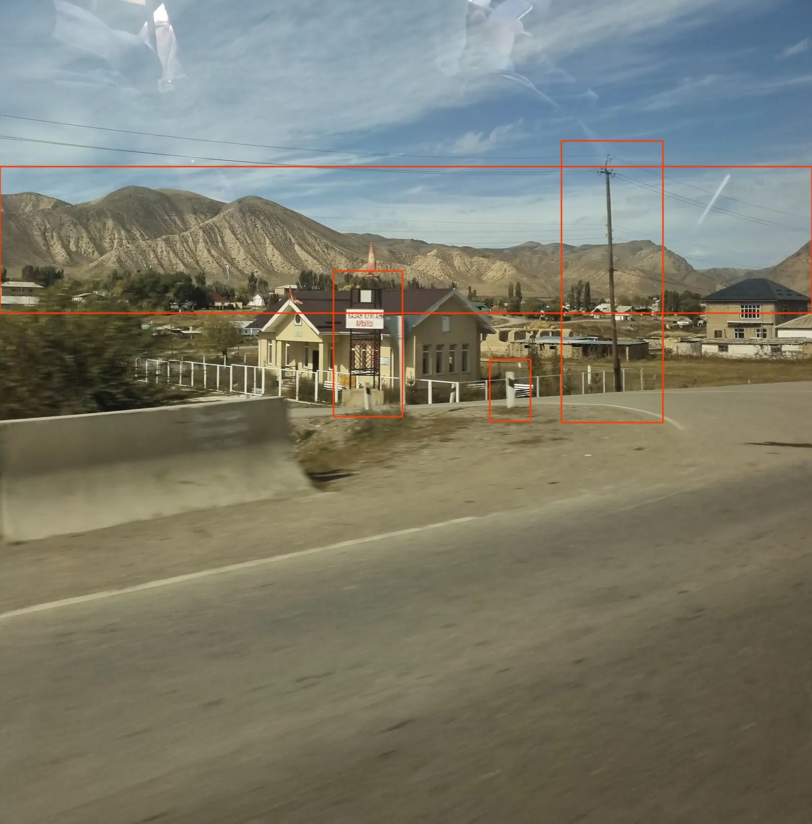 The challenge photo with red boxes: a wide band around the mountain ridge, the sign on its black frame, a black and white roadside post, and a wooden utility pole on the right