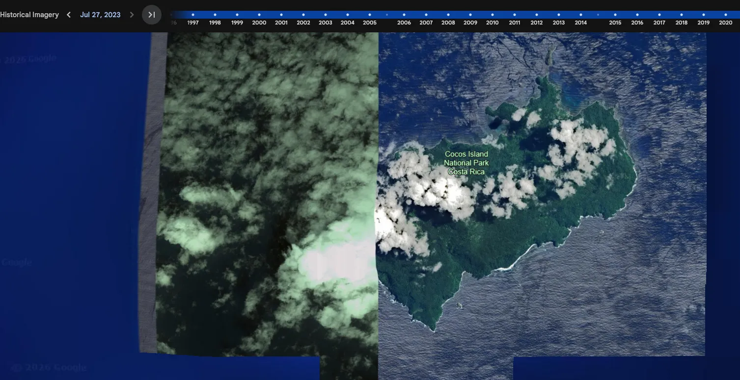 Google Earth over Isla del Coco with the historical imagery timeline open at Jul 27 2023: a dark, heavily clouded tile abutting a clean tile that shows the island in full, labelled Cocos Island National Park, Costa Rica