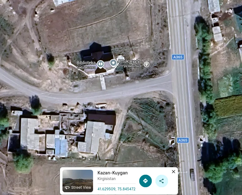 Google Maps satellite view of the junction: a dark-roofed building next to the A365 at the corner of a side road, labelled Biblioteka and Ottuk Ayyly