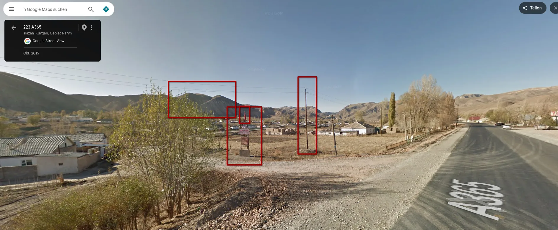 Google Street View on the A365 at Kazan-Kuygan, dated October 2015: red boxes around the mountain ridge, the same sign frame on a concrete base with a small red flag, and a wooden utility pole, next to an empty lot with a gravel side road