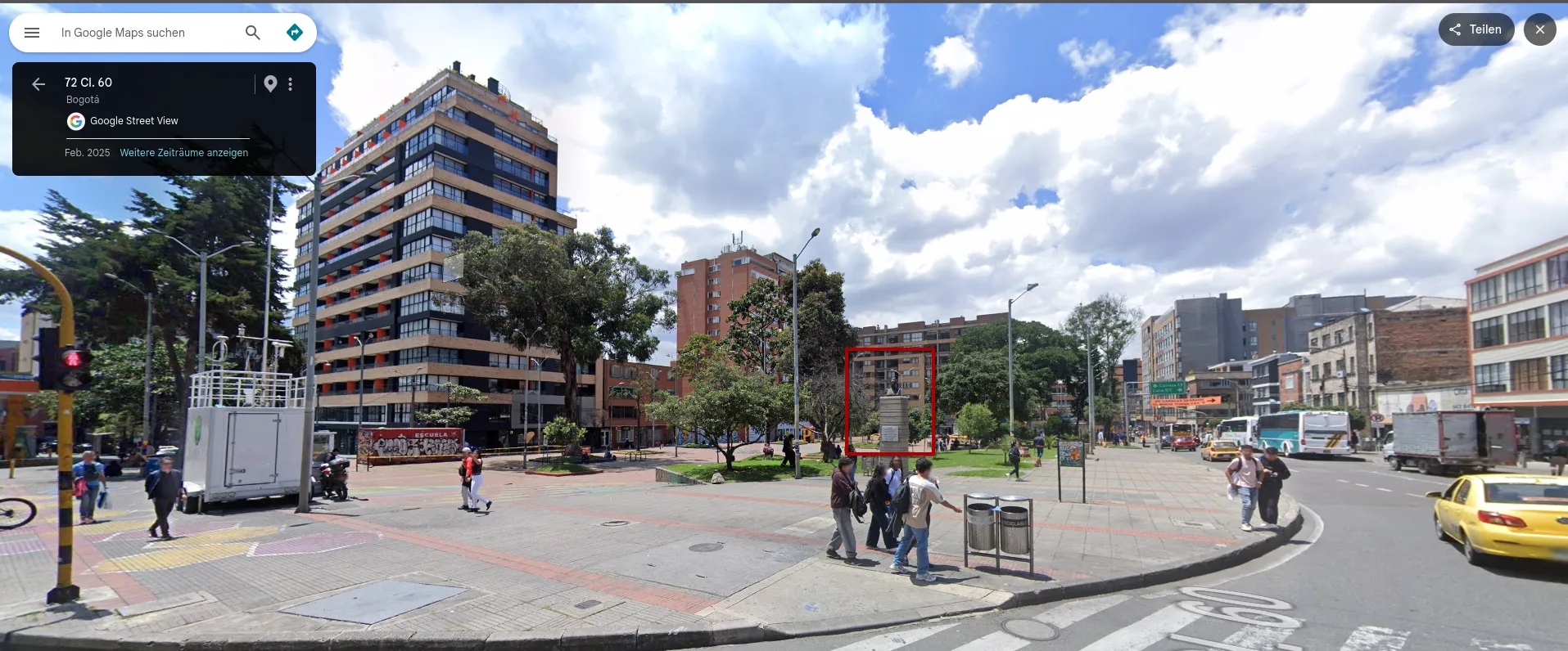 Street View from the same point at Carrera 7 and Calle 60, turned towards the park: the traffic light pole and the white trailer on the left edge, a high-rise with orange accents behind trees, and in the middle a red box around a bust on a tall stone pedestal at the corner of the park