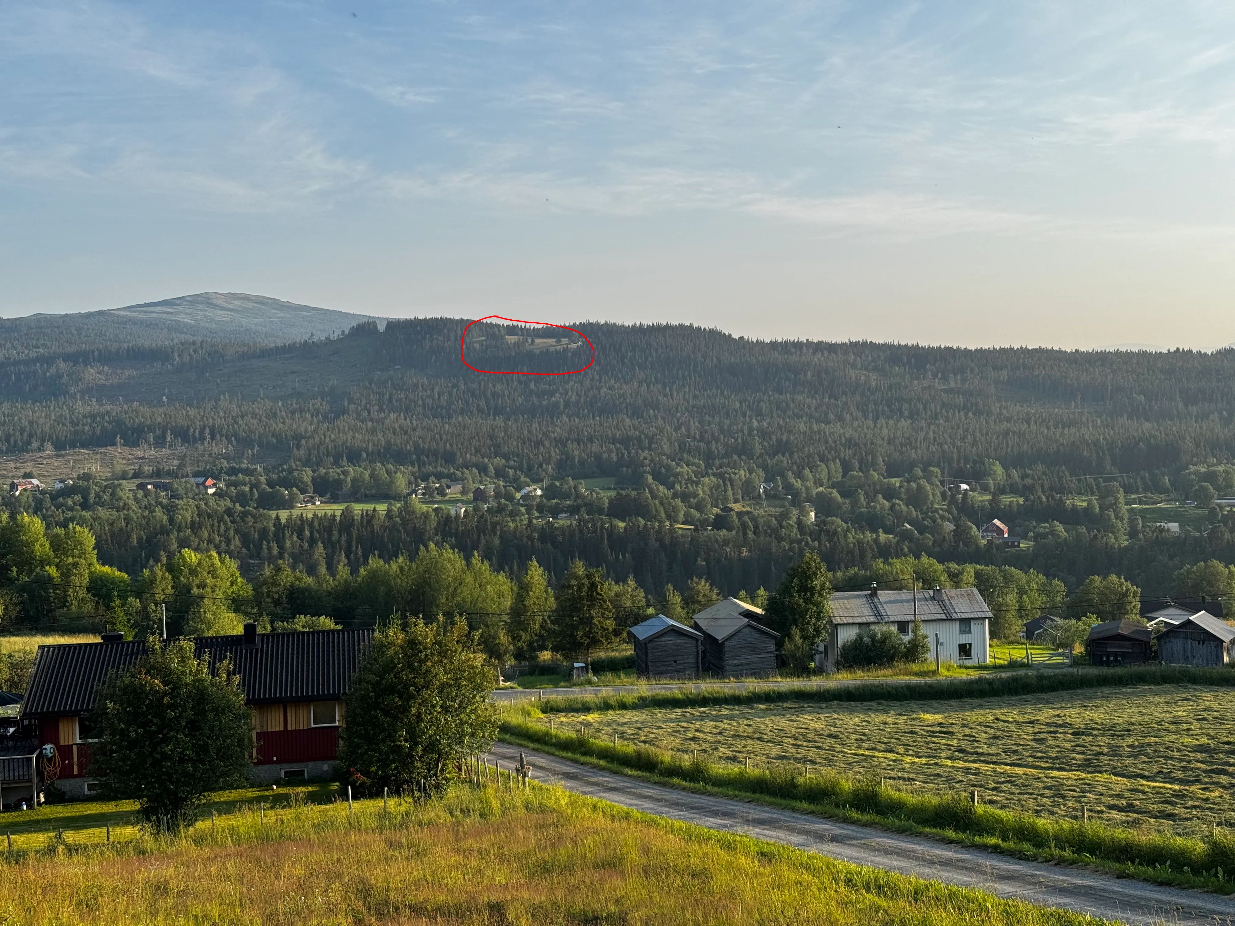 The challenge photo with a red circle marking a small clearing with buildings on the ridge crest